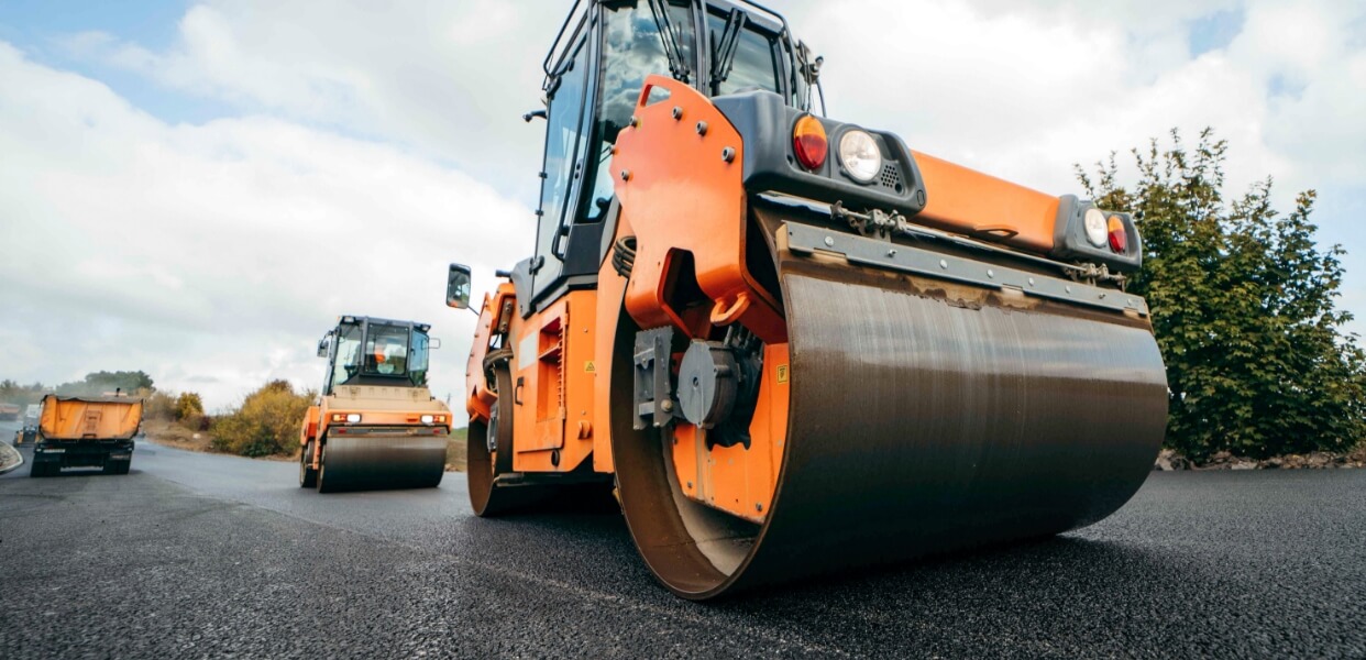 Road rollers applying a new layer of asphalt on a road.