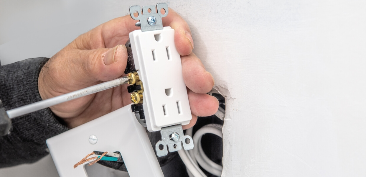 Electrician installing a new power outlet in a wall.