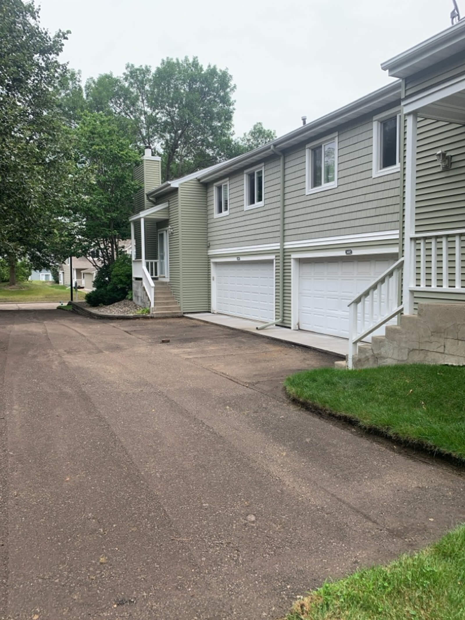 A clean driveway and exterior view of residential townhomes, showcasing the siding and roofing after maintenance or renovation work.