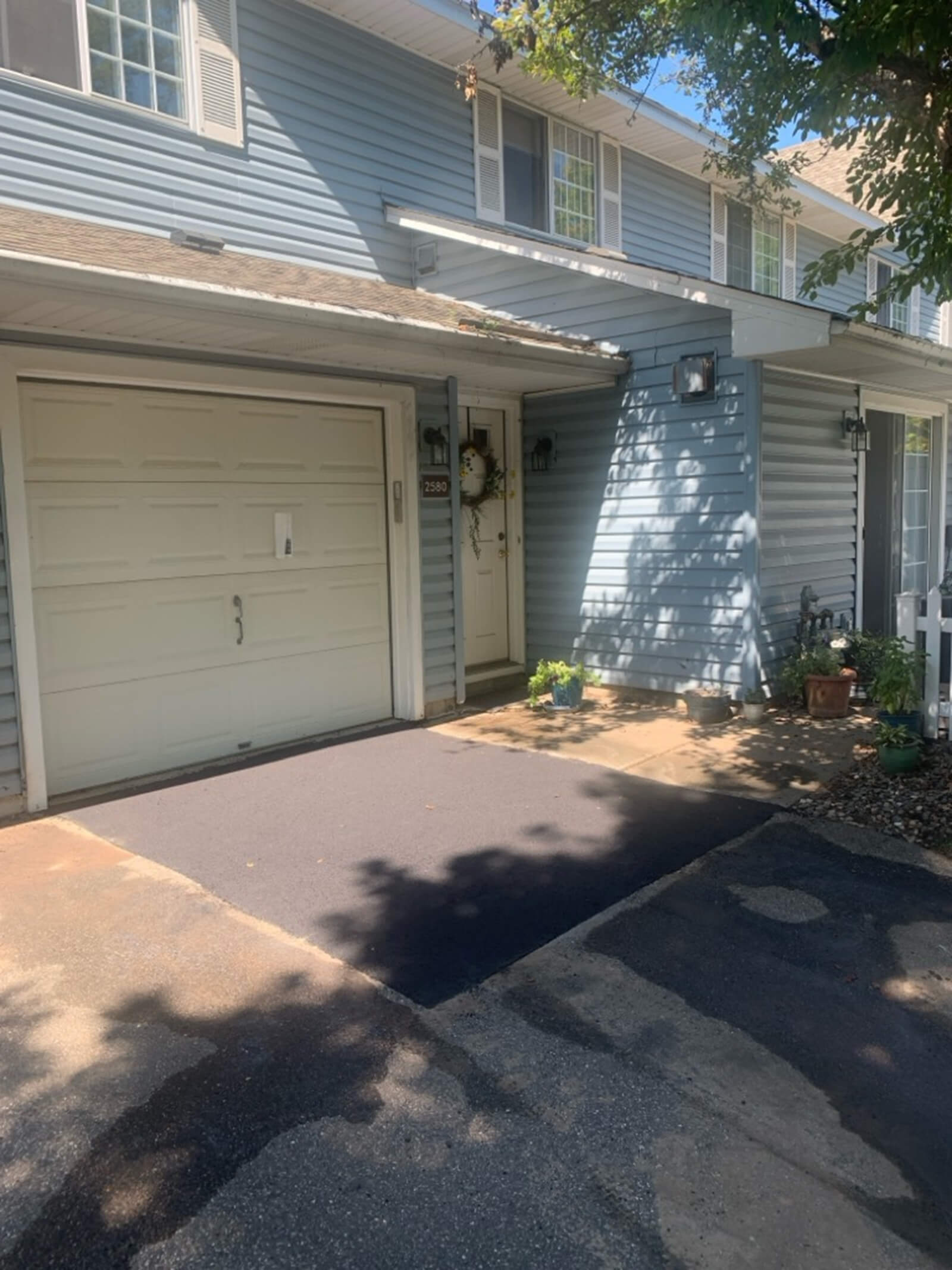 A newly paved driveway in front of a two-car garage, showing the smooth finish and well-maintained exterior of the home.