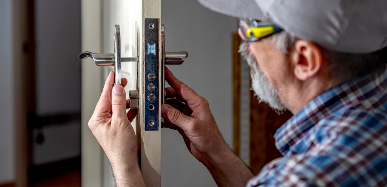 Handyman installing a new door lock on a wooden door.