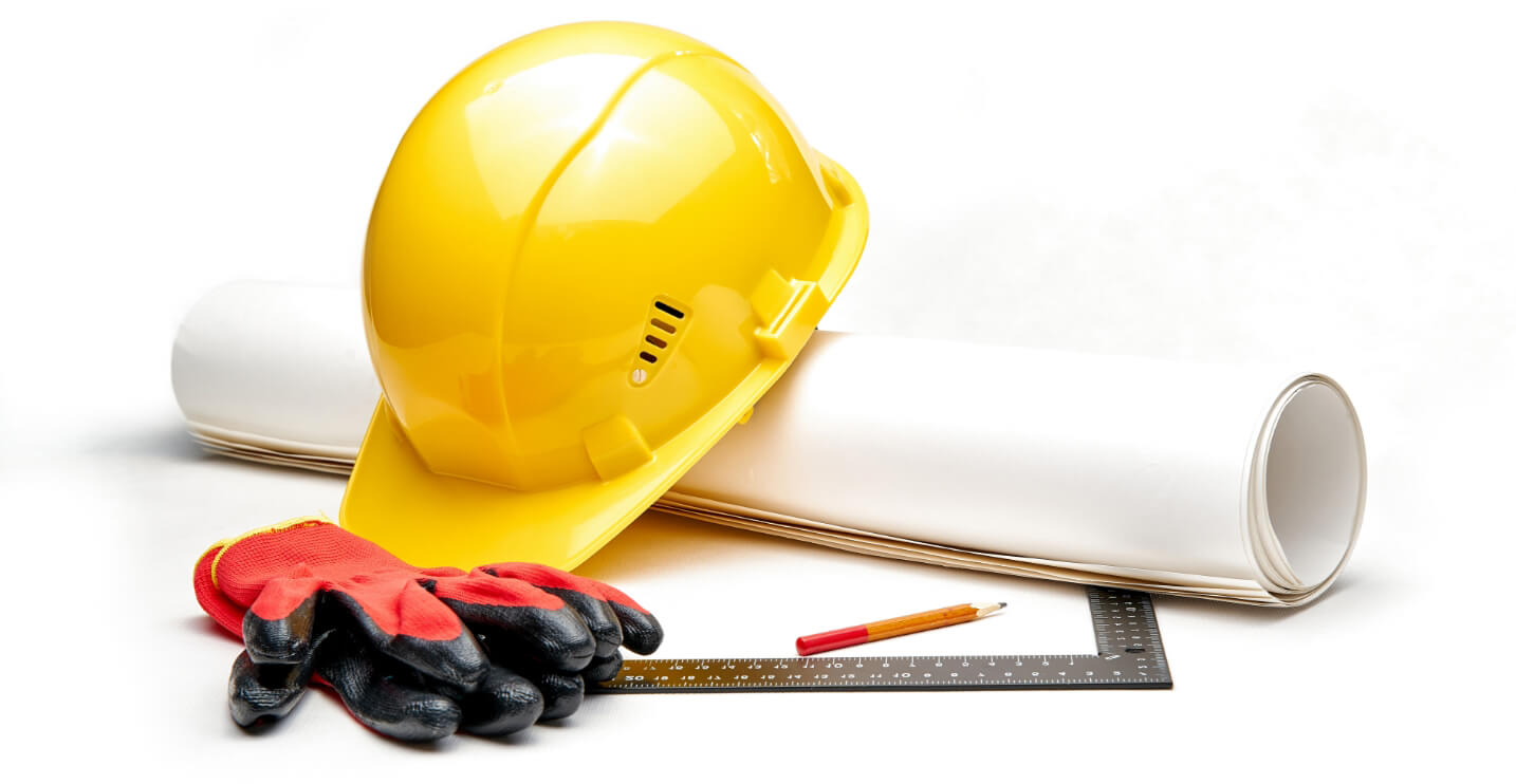 Close-up of a yellow hard hat, blueprint, and construction tools on a desk.