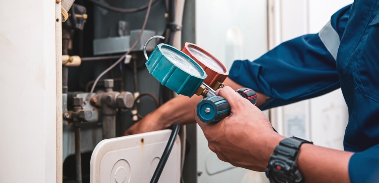 Technician checking pressure gauges on an HVAC system.