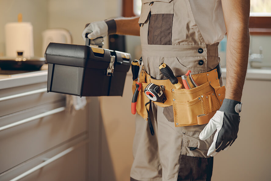 A technician carrying a toolbox with various tools for maintenance services.