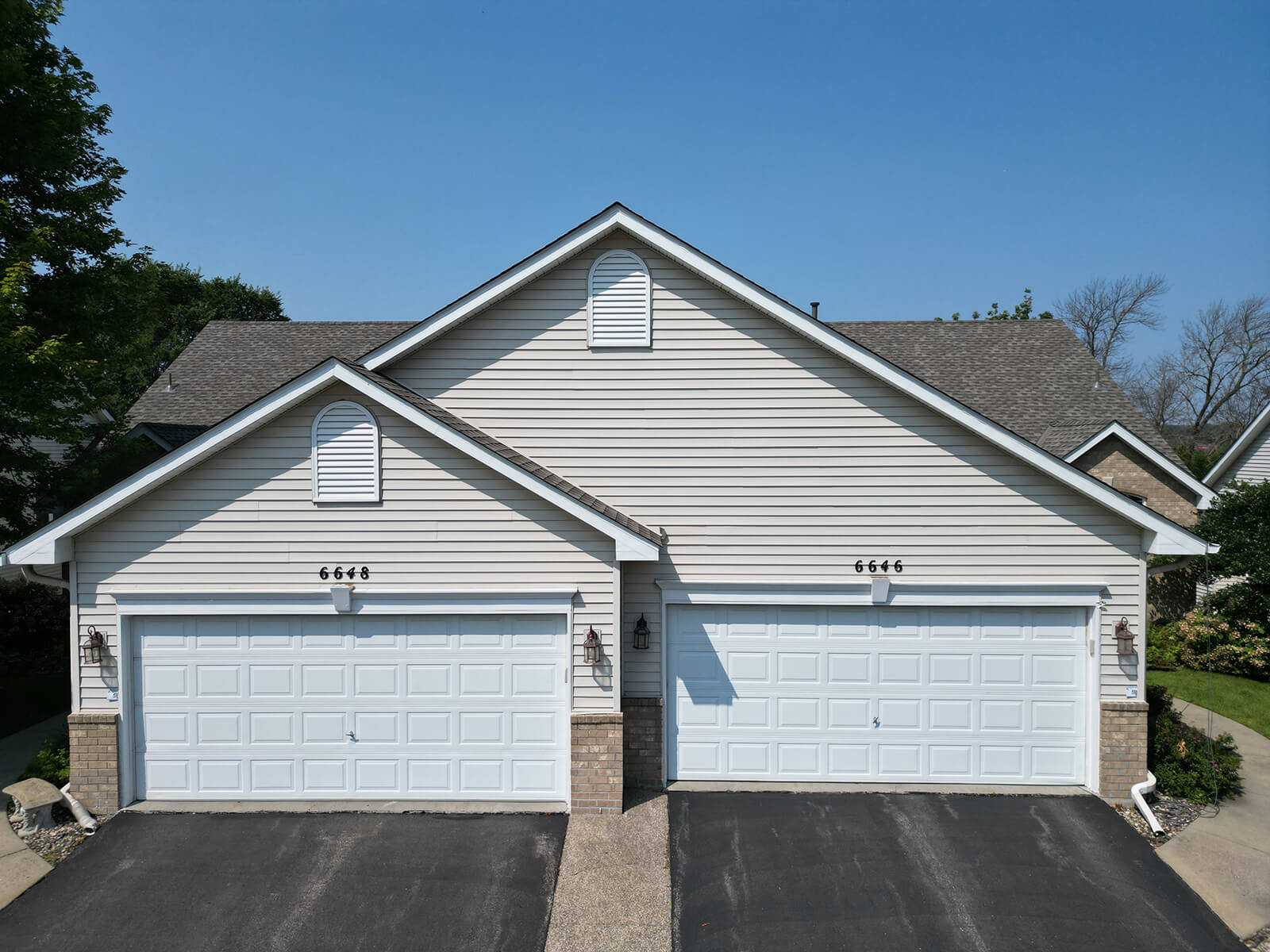 A front view of a house with matching garage doors, showing a clean driveway and the freshly painted exterior of the property.