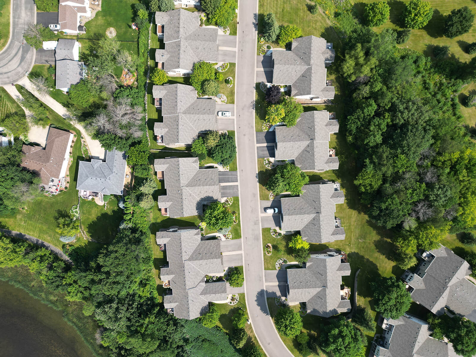 A top-down aerial view of a residential neighborhood, showcasing rows of homes with well-kept roofs and green spaces between properties.